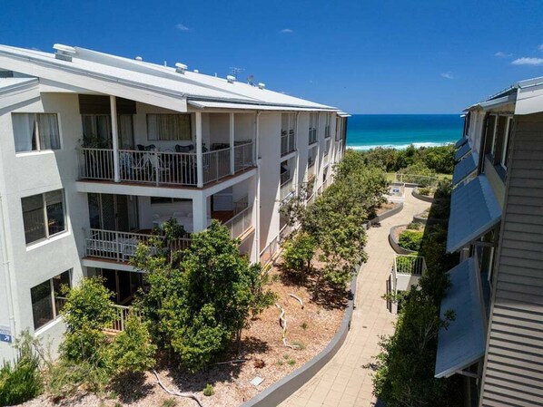 A multi-story building with balconies overlooking a beach.