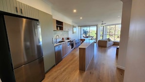 A modern kitchen with a stainless steel refrigerator, wooden cabinets, and a large island.