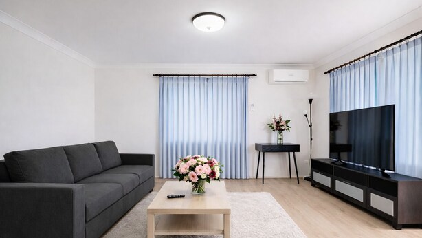 Un saló modern amb un sofà, una taula de centre, una televisió i una taula auxiliar amb un ram de flors.