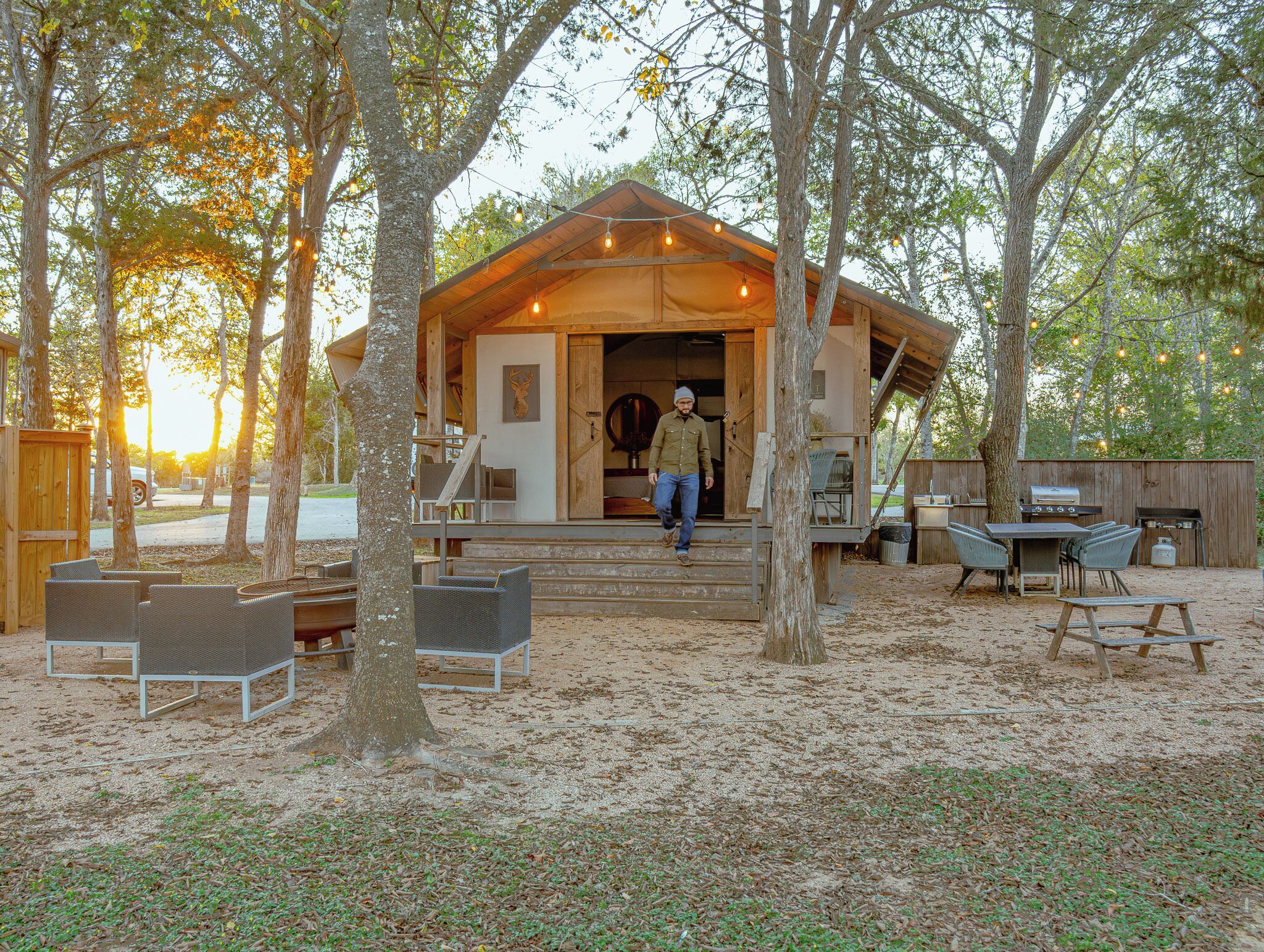 A rustic cabin with a porch, outdoor seating, and a grill area.