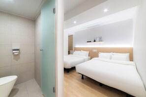 Een hotelkamer met twee bedden, een toilet en een douche.