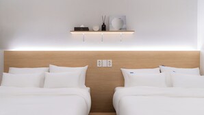 Ein Hotelzimmer mit zwei Betten, einem Holz-Kopfteil, einem Regal mit Dekoration und einer Wandsteckdose.