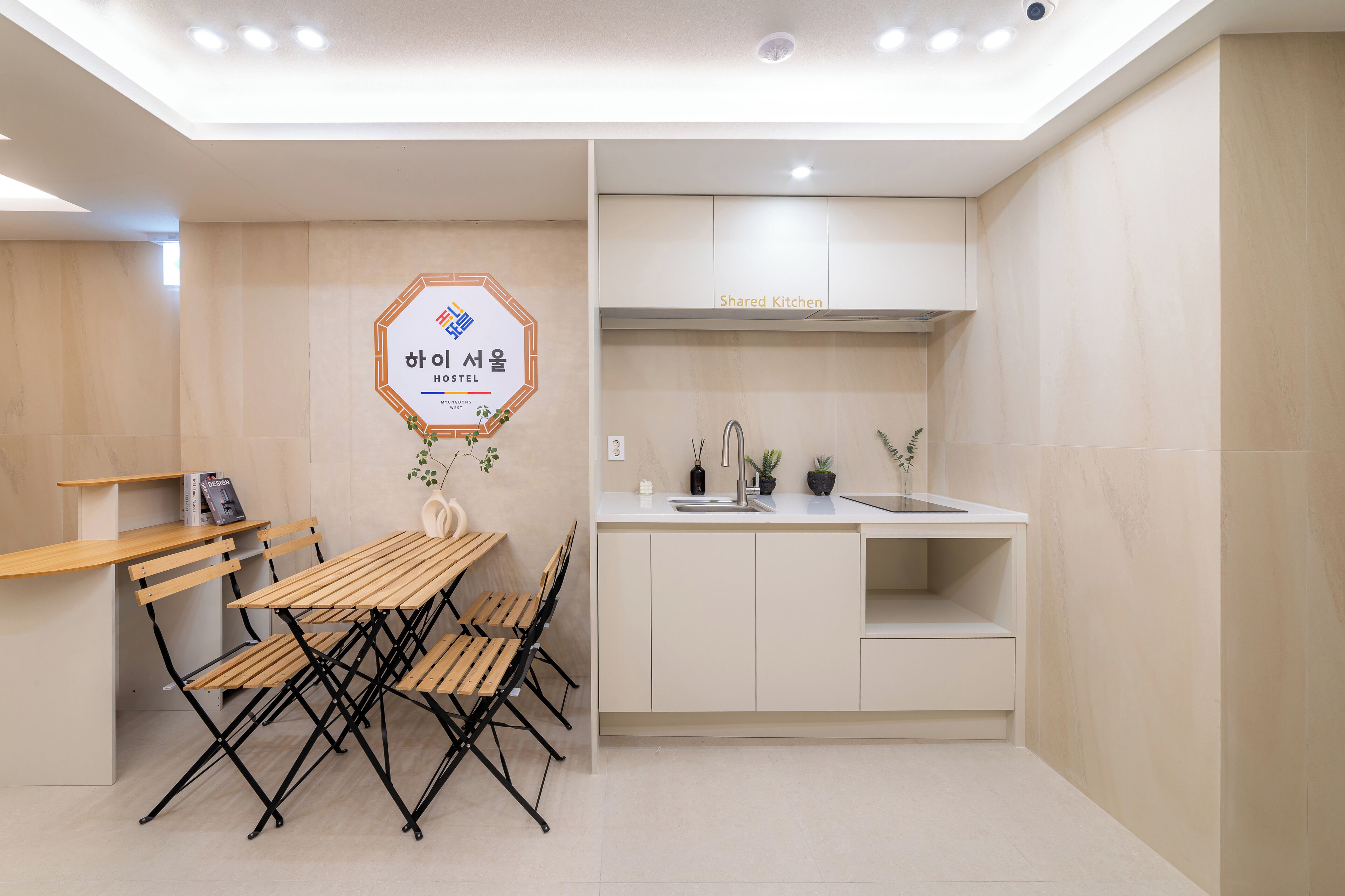 A modern kitchen with a dining area. There is a sign on the wall indicating a shared kitchen.