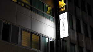 Ein Schild mit koreanischem Text, das auf ein Hostel hinweist.