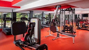 A modern gym with various exercise equipment, large windows, and a red floor. - Garza Blanca Resort & Spa Los Cabos (Cabo San Lucas)