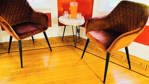 Two velvet armchairs with black legs, a small round table with a glass of orange drink, and a wooden parquet floor. - Spacious room in Federal Hill, Downtown with a private bathroom. (Providence)