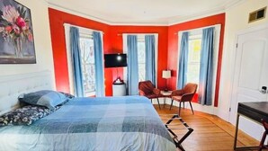 A bedroom with a bed, a desk, two chairs, a TV, and a painting on the wall. - Spacious room in Federal Hill, Downtown with a private bathroom. (Providence)