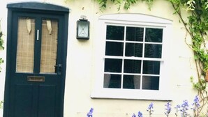 A traditional house with a dark green door, a white window, and a lantern on the wall. - Mews Cottage off Marlborough High Street (Marlborough)