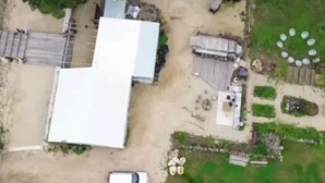 An aerial view of a property with two large white domes, a fenced yard, and a small garden area with circular planters.