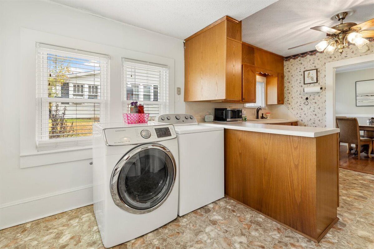 A compact kitchen with a washing machine, wooden cabinets, and a small island.