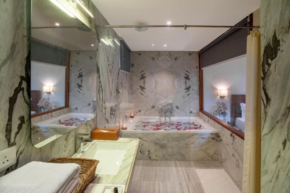 Un baño moderno con tocador de mármol, bañera independiente y un espejo grande.