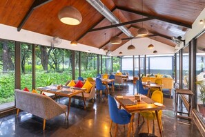 A restaurant with wooden ceiling beams, large windows, and colorful seating.