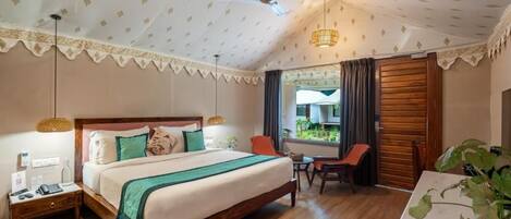 A hotel room with a large bed, a desk, a chair, a ceiling fan, and a window with curtains.