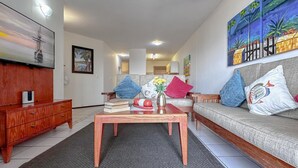 Ein Wohnzimmer mit einer Couch, einem Couchtisch und einem Fernseher an der Wand.