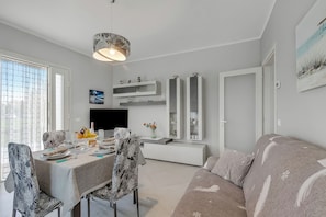 A modern living room with a dining area, a sofa, a TV, and a large window. - Casa Nadia 1.2 Km from Sea with Terrace & Parking, Marina di Massa, Italy (Marina di Massa)