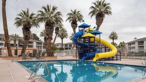 A swimming pool with a water slide and palm trees. - Desert Views Retreat, 8 Bedrooms, Sleeps 24, Community Amenities (St. George)