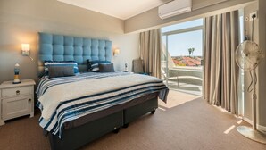 Camera d'albergo con un letto grande, un comodino, una lampada, un condizionatore d'aria e vista all'esterno.