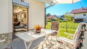 Een terras buiten met een tafel en stoelen, uitzicht op de buurt en een huis op de achtergrond.