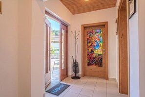 A hallway with a wooden door, a colorful stained glass window, and a doormat with 'HOME' written on it. - Weiss Family Apartment Savinja Hills, Rečica ob Savinji, Slovenia (Rečica ob Savinji)
