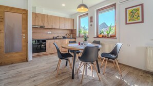Een moderne keuken met houten kastjes, een ronde eettafel met vier stoelen en een hanglamp.