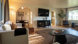 A modern living room with a sofa, coffee table, and a flat-screen TV mounted on the wall. - Central Park Mid-Century Modern Dream (Midland)
