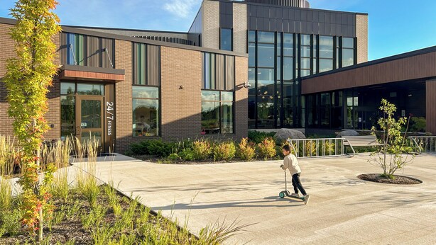 A modern building with a brick facade, large windows, and a paved area with landscaping. - Central Park Mid-Century Modern Dream (Midland)