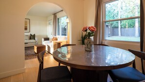A dining area with a round table, chairs, and a vase with flowers. - Central Park Mid-Century Modern Dream (Midland)