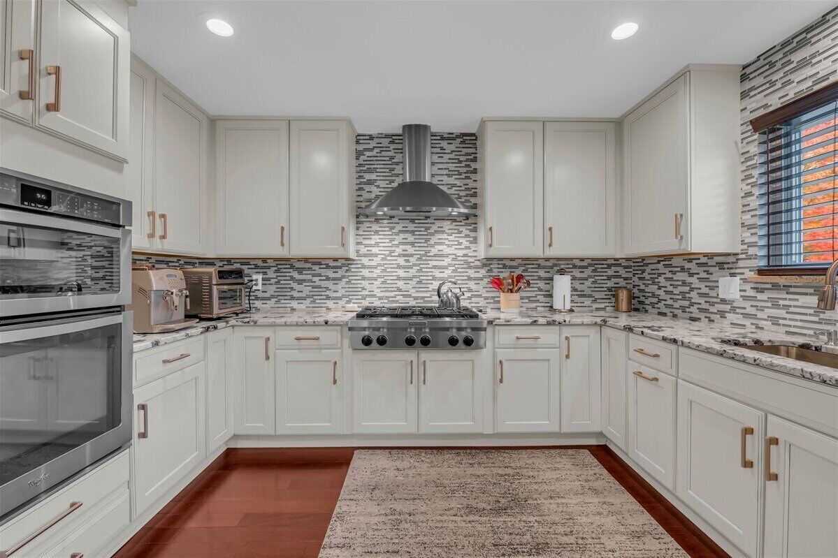 A modern kitchen with white cabinets, a stainless steel range, and a patterned backsplash.