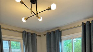 Une chambre à coucher avec un lit, des rideaux gris, une fenêtre et un luminaire au plafond.