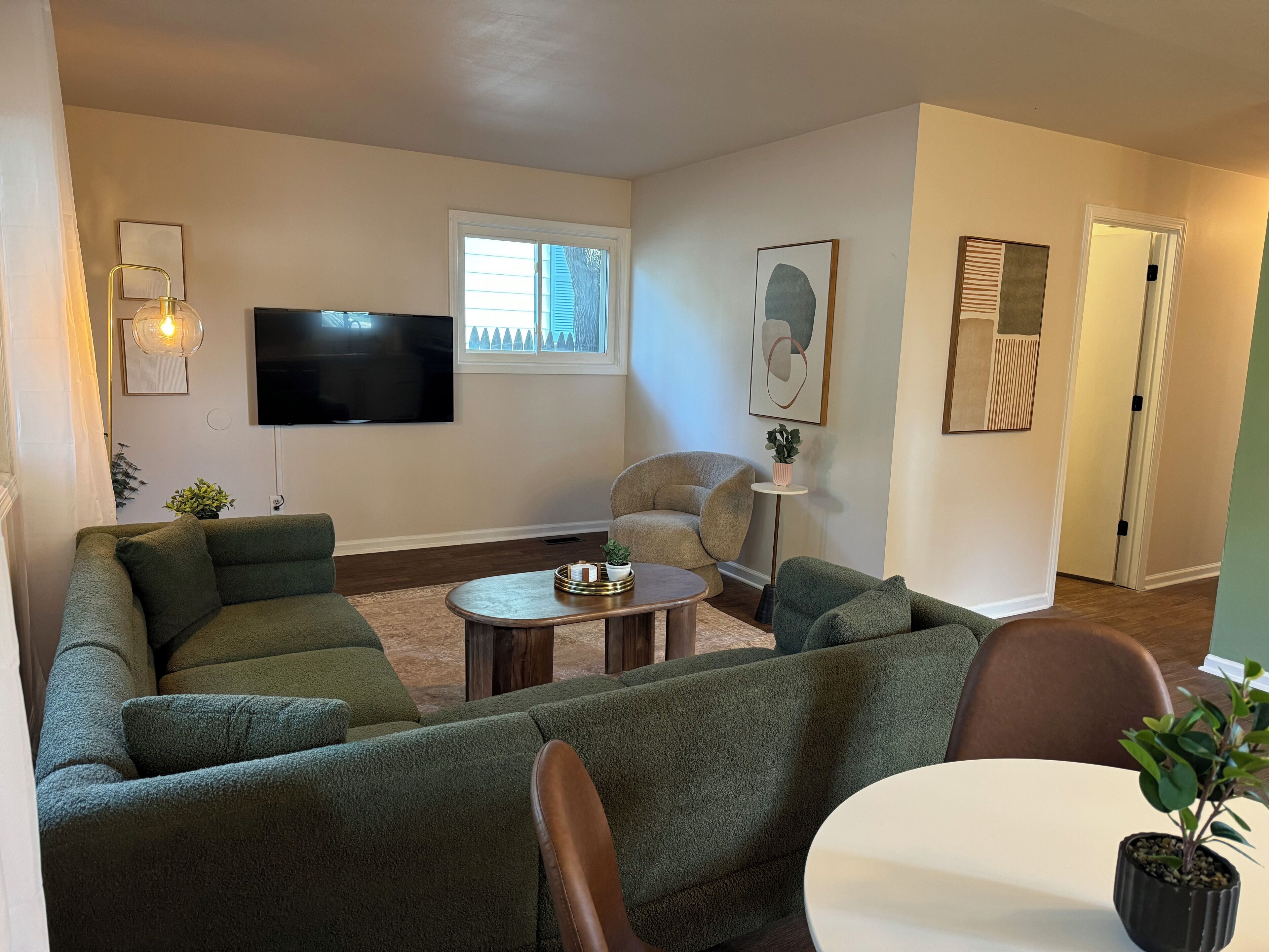 Una sala de estar con un sofá modular, una mesa de centro, un televisor y una planta en maceta.