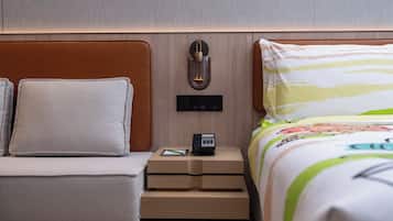 A hotel room with a bed, a nightstand, a lamp, and a power outlet.