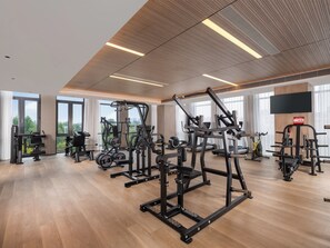 A modern gym with various exercise equipment, large windows, and a flat-screen TV on the wall. - Holiday Inn Beijing Daxing Centre By Ihg (Daxing)