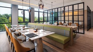 A modern restaurant with a long counter, booths, and a view of the outdoors. - Holiday Inn Beijing Daxing Centre By Ihg (Daxing)