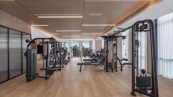 Una palestra moderna con diverse macchine per esercizi, ampie finestre e pavimento in legno.