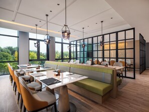 A modern restaurant with a long counter, booths, and a view of the outdoors. - Holiday Inn Beijing Daxing Centre By Ihg (Daxing)