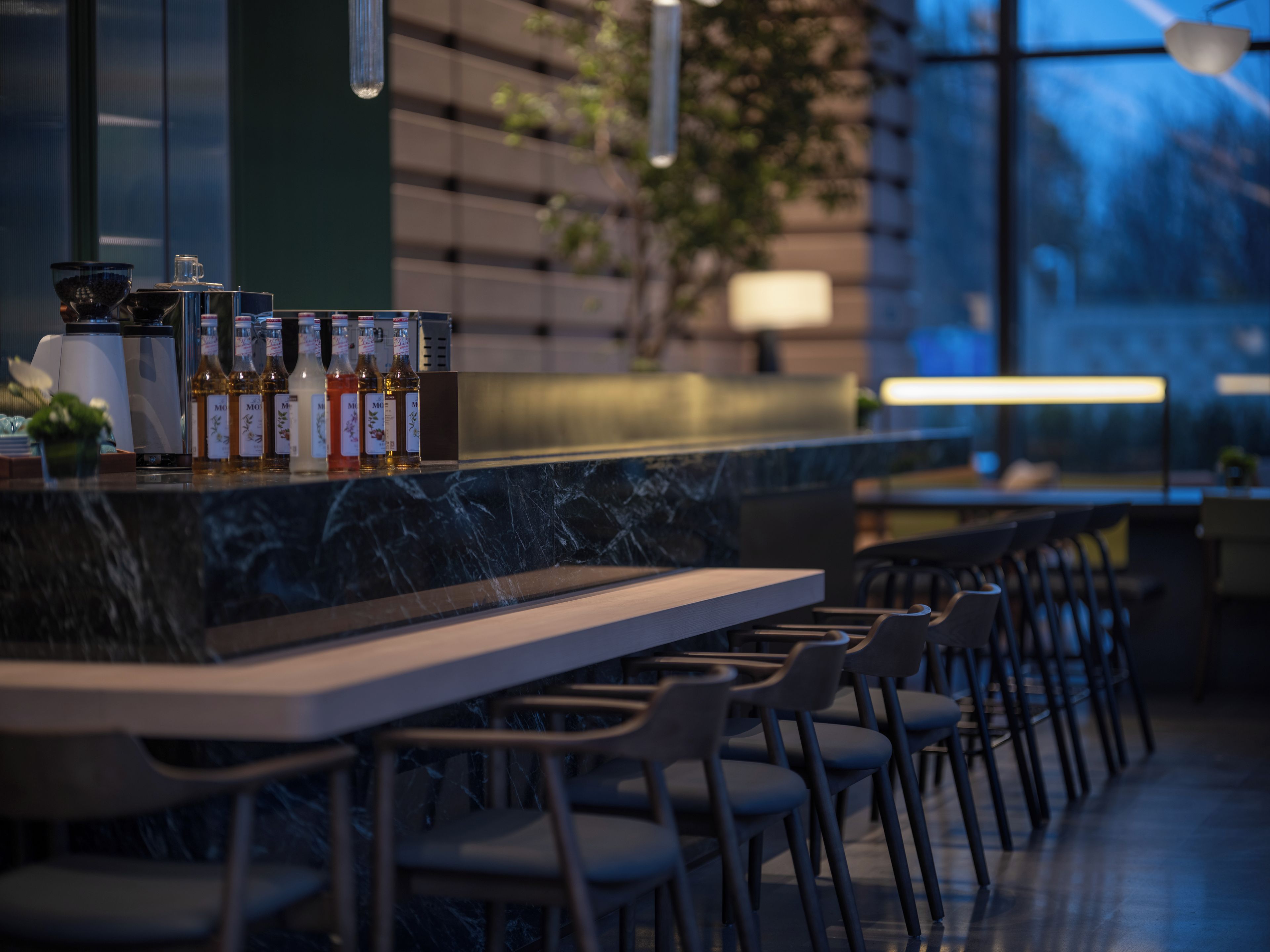 A modern bar area with a marble countertop, neatly arranged bottles, and a row of chairs.