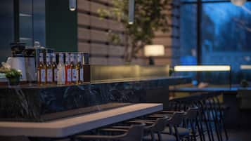 A modern bar area with a marble countertop, neatly arranged bottles, and a row of chairs.