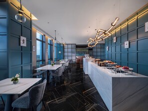 Un restaurant moderne avec un long comptoir, de nombreuses tables et des chaises.