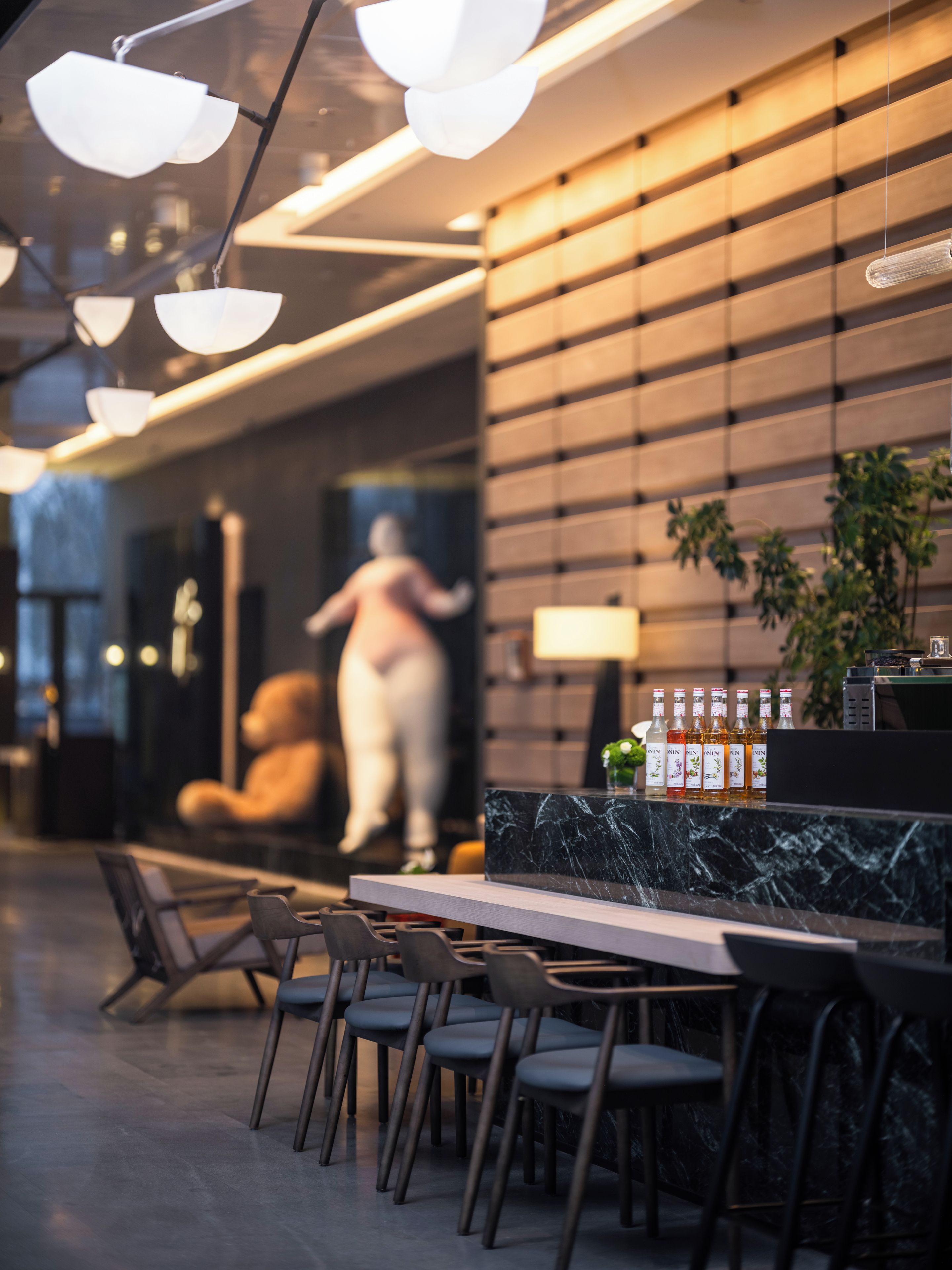 Un intérieur moderne avec un comptoir en marbre, un espace salon et un mur orné d’une grande statue.