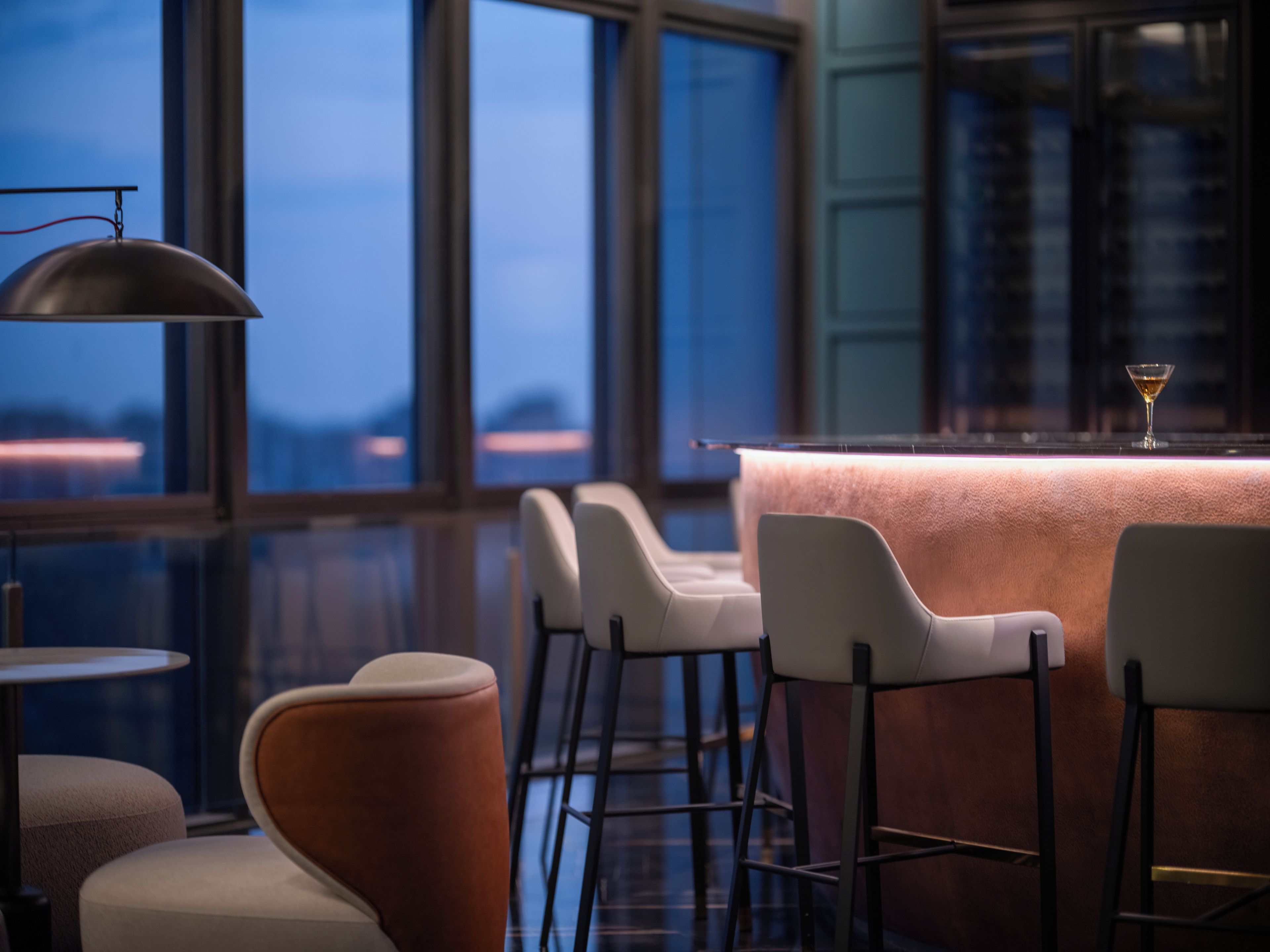 A bar area with a bar counter, stools, and a martini glass.