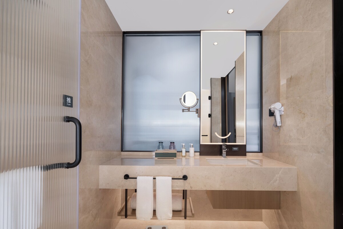 Un baño moderno con un espejo grande, toallero y zona de ducha.