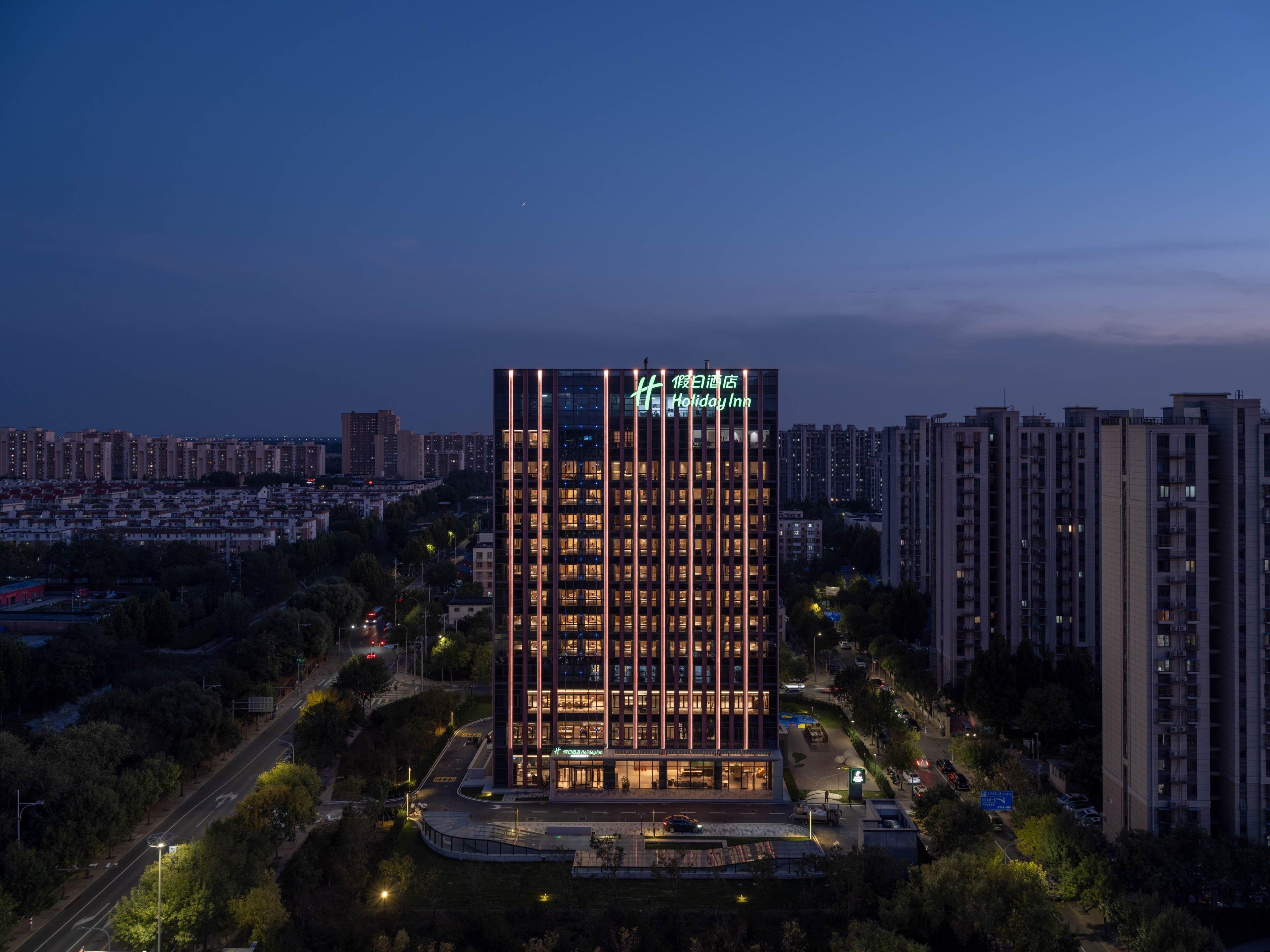 A high-rise Holiday Inn with a modern design, featuring a prominent vertical light strip and illuminated signage.