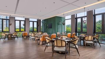 A modern dining area with high ceilings, large windows, and a green accent wall.