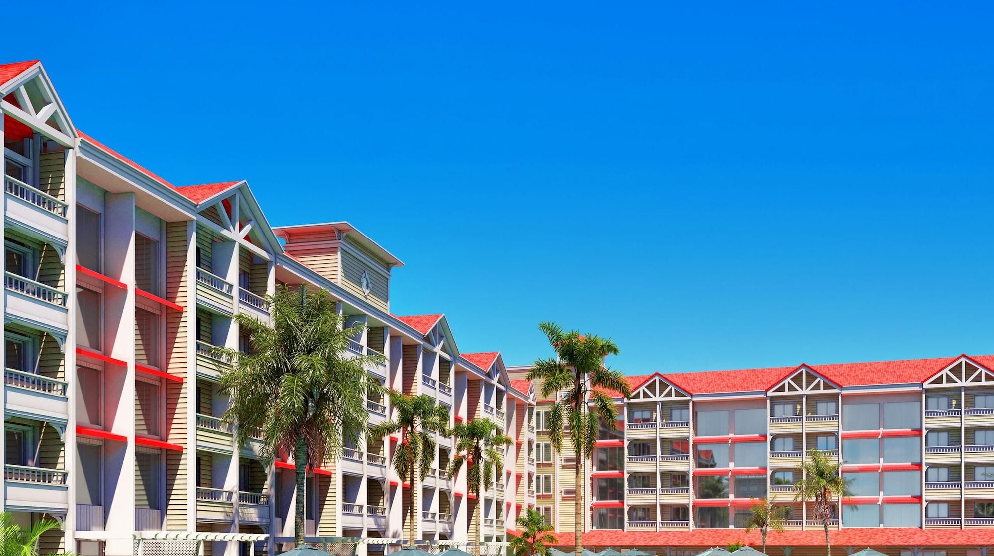 A multi-story hotel with balconies, red roofs, and palm trees.