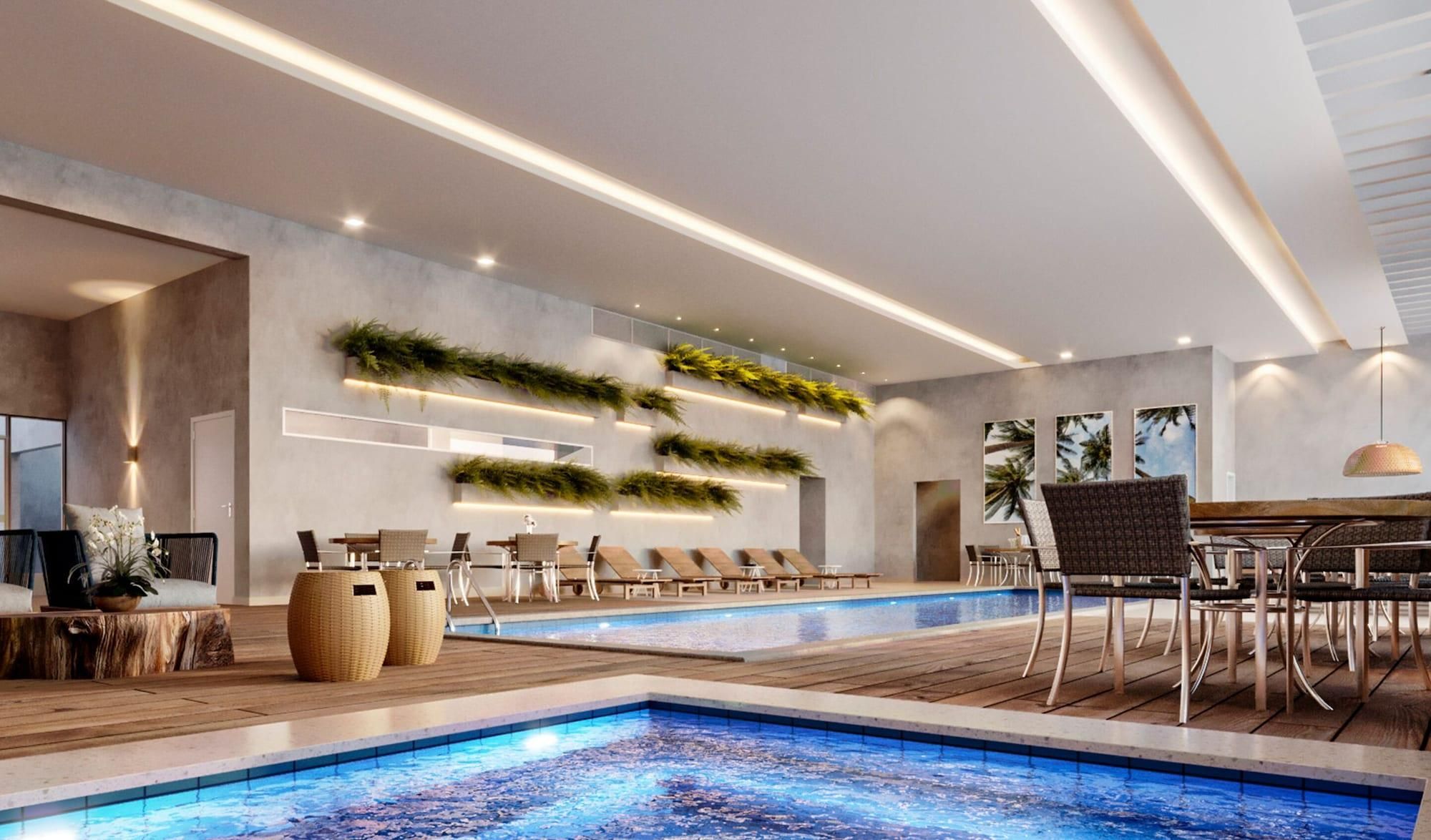 Un área de piscina interior moderna con un amplio espacio de asientos tipo banco, una piscina con diseño de mosaico azul y jardines verticales en las paredes.