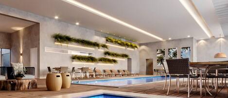 Un área de piscina interior moderna con un amplio espacio de asientos tipo banco, una piscina con diseño de mosaico azul y jardines verticales en las paredes.