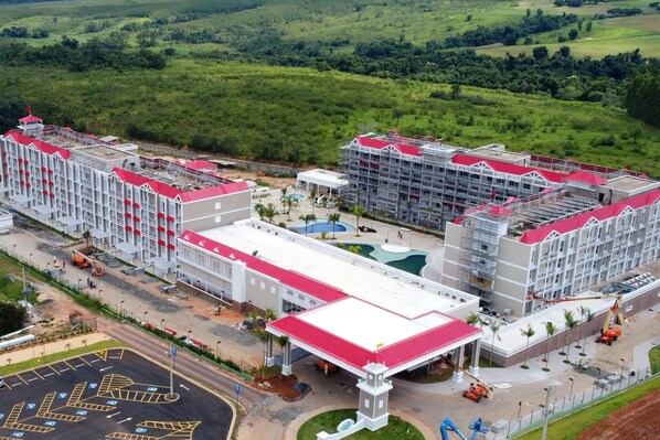 Ein mehrstöckiges Hotel mit rotem Dach, umgeben von üppigem Grün.