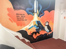 Un mural en la pared con un cohete y un frailecillo, y texto en un idioma extranjero.