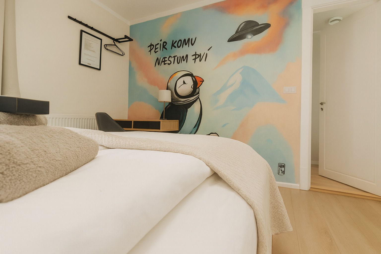 A bedroom with a bed, a desk, and a wall mural.