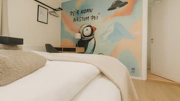 A bedroom with a bed, a desk, and a wall mural.